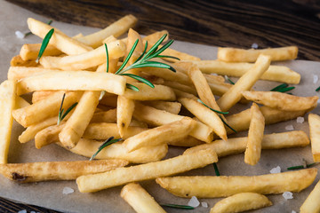 French fries with rosemary on wooden background