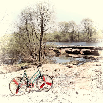 Old bike on off road terrain near the river. Vintage stylization