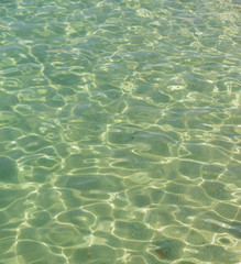 Flecks of sunlight are in clear sea water.