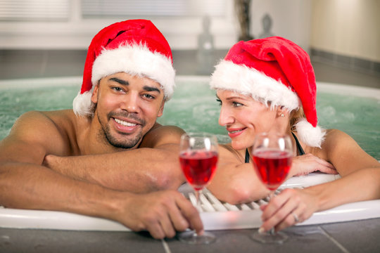 Beautiful woman and man with santa hat relaxing in hot tube at sp