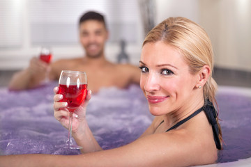 Romantic couple drinking red wine in hot tub