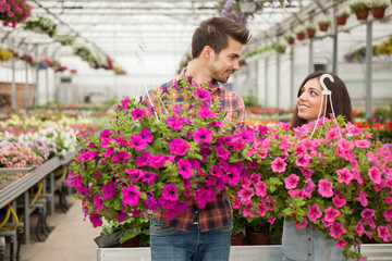 Young smiling florists man and woman working in the greenhouse