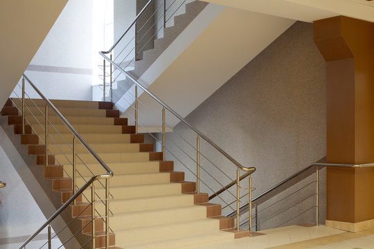 Brown staircase with metal railing, gray wall