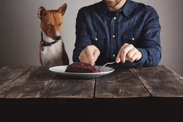 Foto op Canvas Man cuts piece of steak for lovely dog © BublikHaus