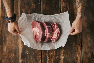 Cercles muraux Steakhouse topview hands hold white paper three raw steaks