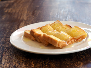 Buttered toast with sweetened condensed milk sliced on white dish