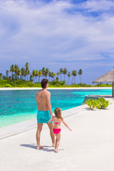 Fototapeta na wymiar Happy father and his adorable little daughter at tropical beach having fun