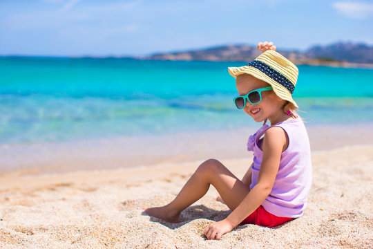 Adorable little girl at white beach during tropical vacation