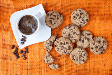 Obraz na płótnie Canvas Chocolate chip cookies and cup of coffee shot on jute colored cl