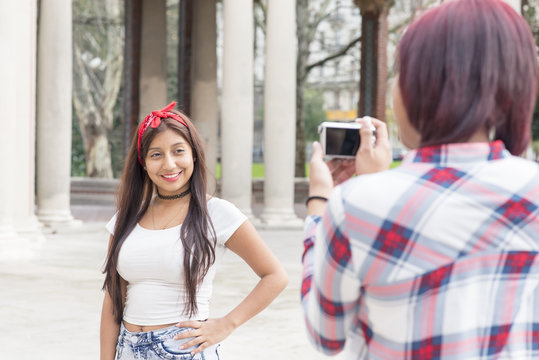 Young woman taking pictures of her friends in the park.