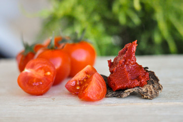 Tomato paste and cherry tomatoes on wooden table in nature