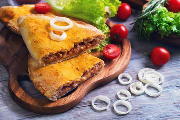 Closed pizza calzone on a light wooden background