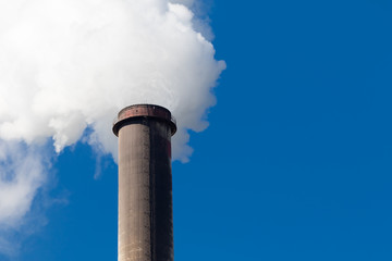 Industrial exhaust pipe with smoke against the sky