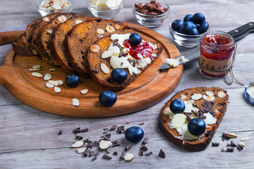 Obraz na płótnie Canvas On a light wooden table sliced bread with fruits and nuts