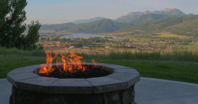 A fire pit blazes in front of a beautiful mountain view.