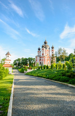 Beautiful Orthodox church in green forest and blue spring sky  