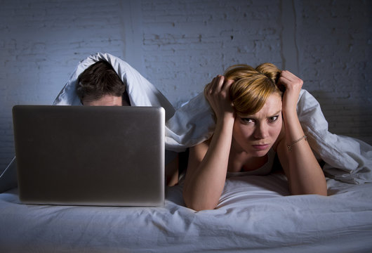 Young Wife Upset Unsatisfied And Frustrated In Bed While Husband Work On Computer Laptop Ignoring Her