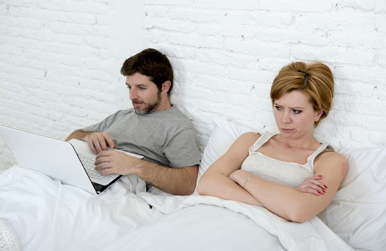 Attractive Woman Feeling Upset Unsatisfied And Frustrated In Bed With His Husband While The Man Work On Computer Laptop Ignoring Her