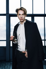 Portrait of a young handsome man, posing on the urban geometric background. Model wearing classic black and white clothes. City lifestyle. Male fashion, street style concept. 