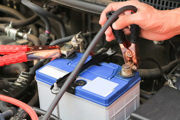 Car mechanic uses battery jumper cables charge a dead battery.