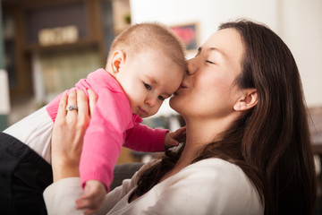 Pretty young mom kissing her baby girl