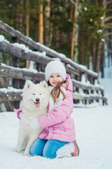 Little girl and dog Samoyed winter outdoors