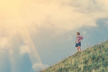 Young girl looking into the distance up against the sky and hillside