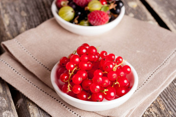 bowl of red currant on wooden background, horizontal close-up