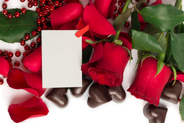 Red rose petals, red roses and candies in a shape of a heart