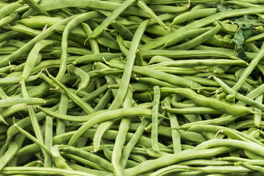 Pile of fresh green bean legumes at farmers market stall.