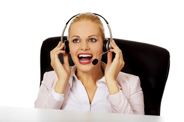 Smile helpline operator sitting behind the desk and talking through a headphones