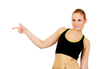 Young athletic woman pointing for copyspace or something