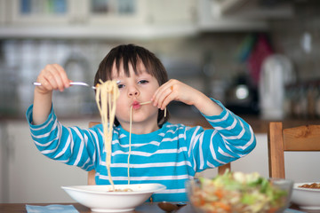 Cute little boy, eating spaghetti at home for lunchtime