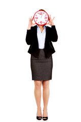 Business woman covering face with a clock