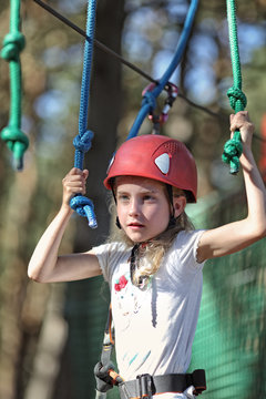 pensive girl in a helmet took up the challenge and goes on an adventure ropes course