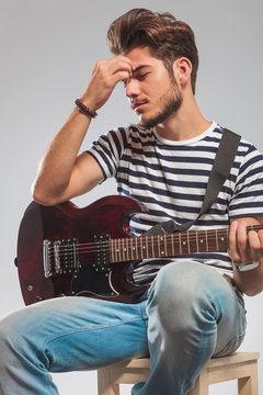 guitarist playing instrument seated while thinking