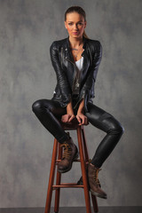attractive rocker woman in leather posing seated in studio