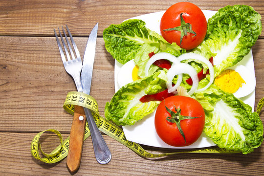 table salad with cutlery on wooden background