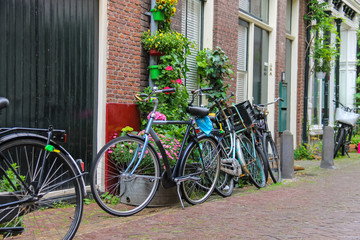 Parked bicycles near the brick house on the narrow street