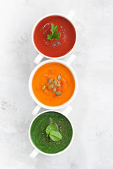 assortment of colorful vegetable cream soup on white background