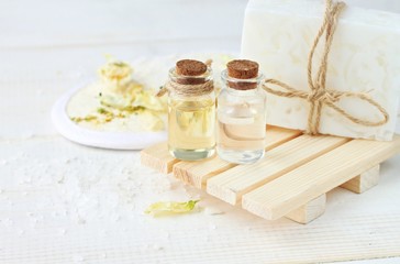Fototapeta na wymiar Herbal spa cosmetic products. Essential oils, soap bar, sea salt. Soft focus, light creamy tones.