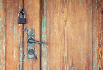 Old weathered wooden doors with rusty door handle and padlock