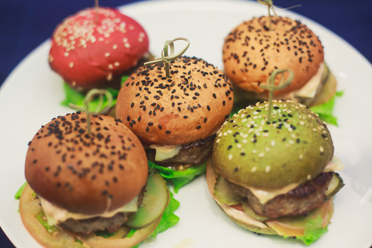 Beautifully decorated catering banquet table with different colored hamburgers burgers sandwiches on a plate on corporate christmas birthday party event or wedding celebration