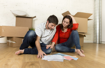 Fototapeta na wymiar happy American couple sitting on floor moving in new house looking blueprints