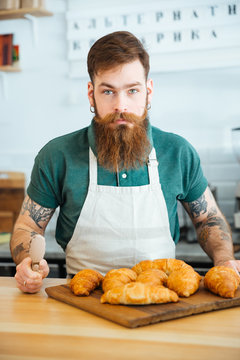 Handsome bearded man barista with croissants in coffee shop