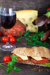 Homemade Italian Sub Sandwich with salami, cheese, salad and glass of red wine