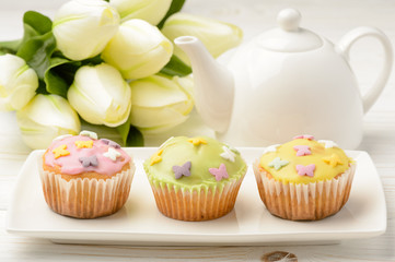 Muffins covered with icing sugar on white plate.