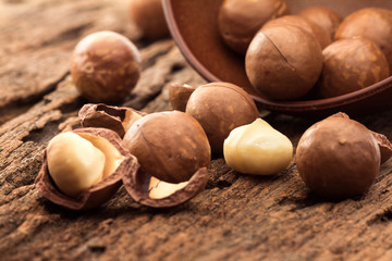 Close up macadamia nuts on wooden plate - obrazy, fototapety, plakaty