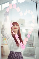 Obraz premium Smiling hipster woman doing a heart in post-it