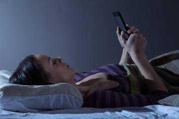 Young woman checking the time early in the morning. It's time to get up for work.
